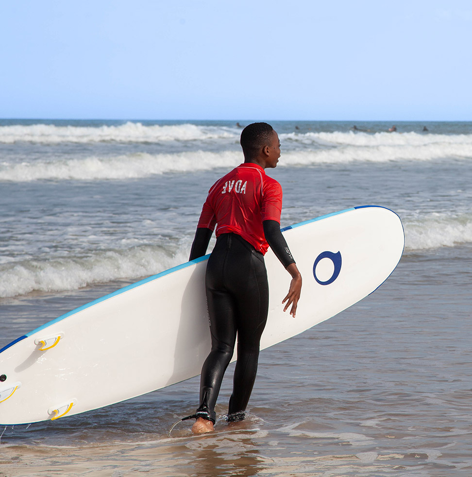 Un garçon avec une planche de surf qui regarde l'horizon