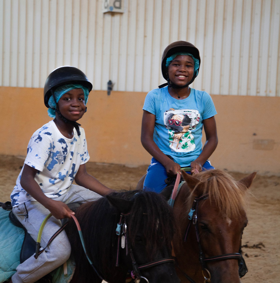 Deux enfants qui sourient sur des poneys